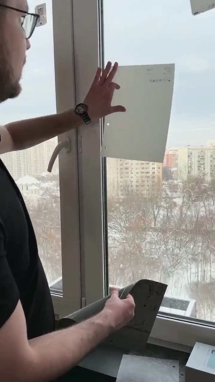 Мастер TENI прикладывает образец ткани к окну заказчицы
